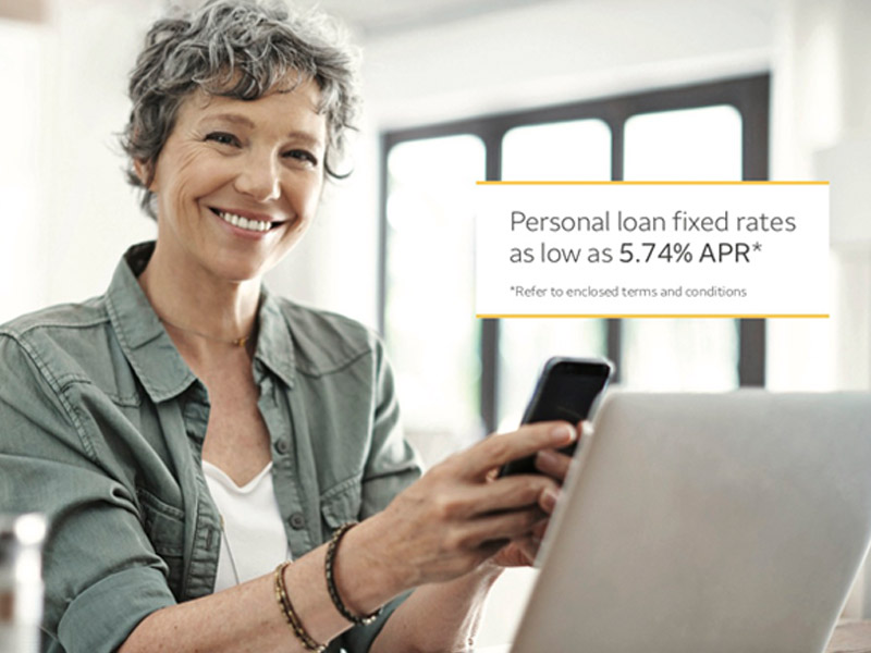 A smiling woman holding a phone in front of a laptop. Text over the image reads ‘Personal loan fixed rates as low as 5.74% APR’.